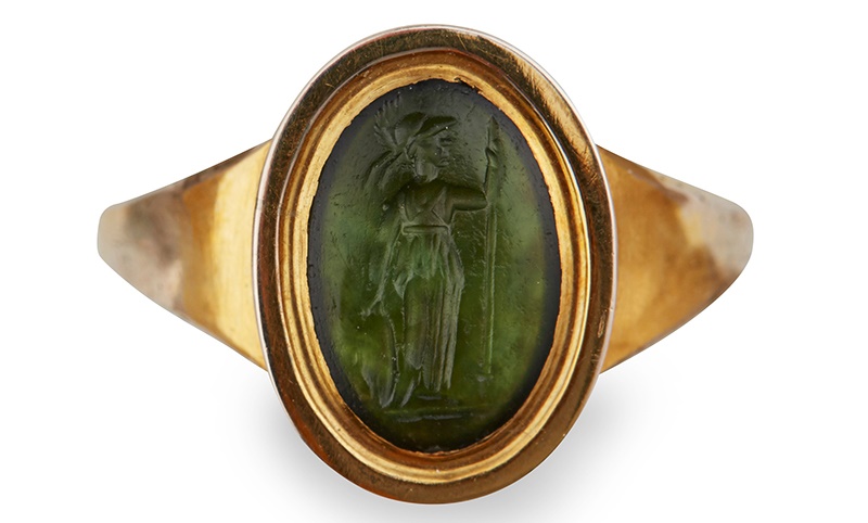 A GOLD MOUNTED INTAGLIO RING the green translucent stone of oval form with a standing classical lady holding a spear and something in the other hand, simple mount | Ring size: Q/R, intaglio height: 1.1cm | Provenance: Lots 111 - 119 from a private collection. | Sold for £1,750*