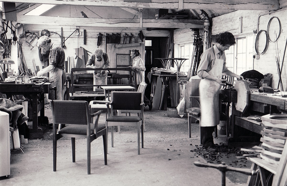 (fig. 4) The Barnsley Workshop in about 1981. Left to right are George Taylor, Oskar Dawson, Tania Barnsley and Mark Nicholas. The image is believed to show Oskar Dawson working on the desk comissioned by John Minoprio (lot 58). Photo by Donald C. Eades, © Edward Barnsley Educational Trust.