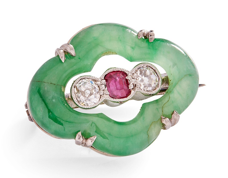 LOT 303 | An early 20th-Century jadeite, diamond and ruby brooch | Width: 2.1cm | £700 - £1,000 + fees